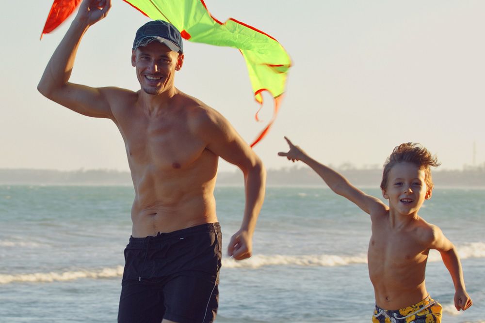 Photo of a man and young boy running on a beach